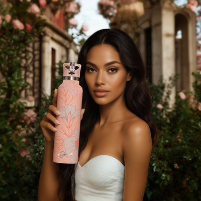Woman holding a peach water bottle with floral design in a Grecian outdoor setting